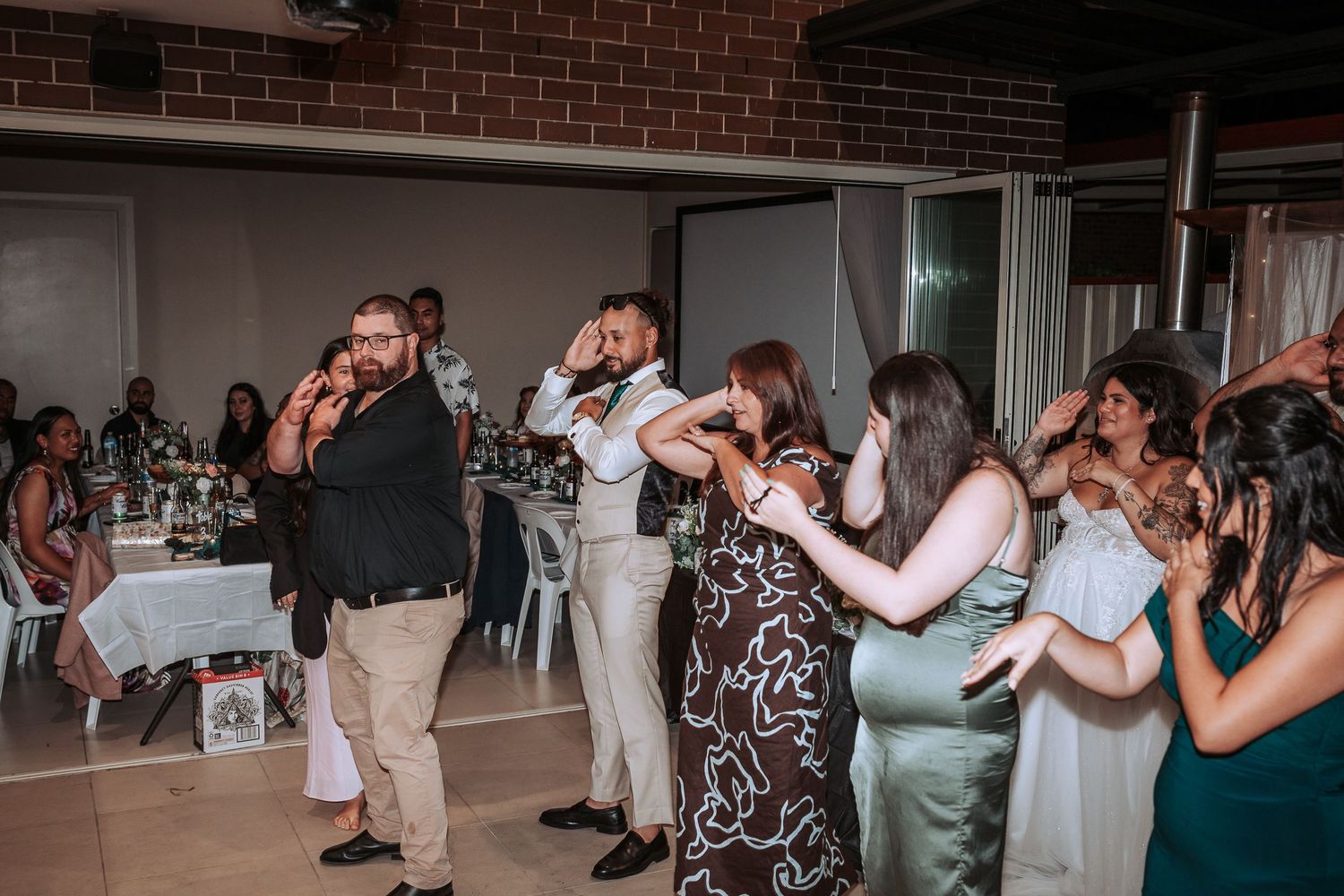 Wedding guests dancing and enjoying themselves on the dance floor at an indoor reception.