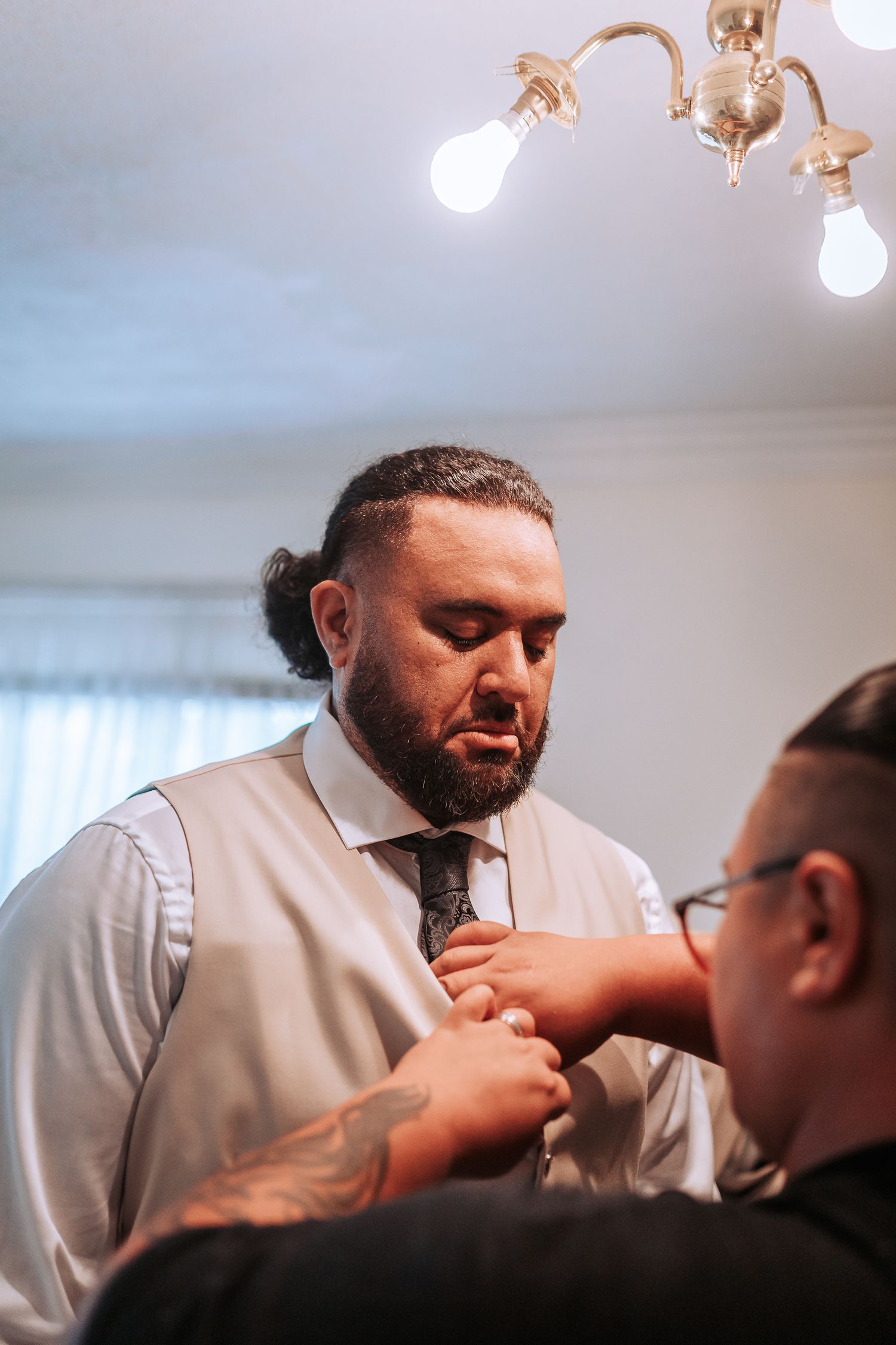 Person in formal attire having their tie adjusted before an event.