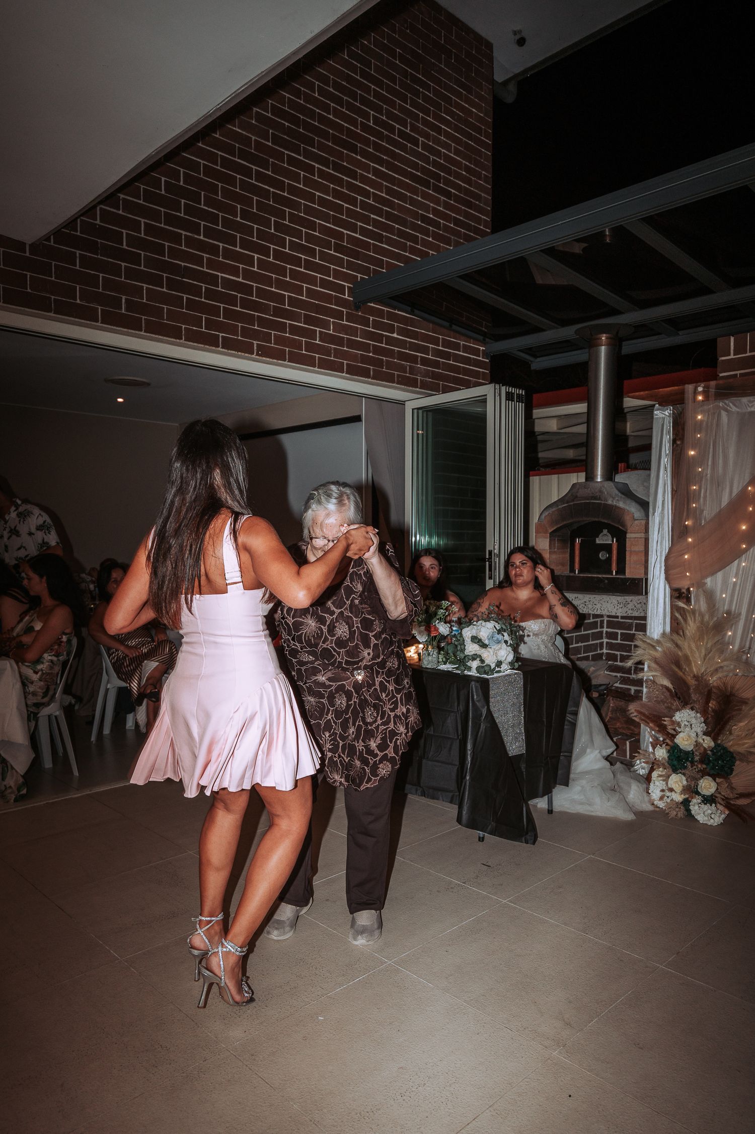 Guests dancing together on the reception floor with brick walls and elegant decor.