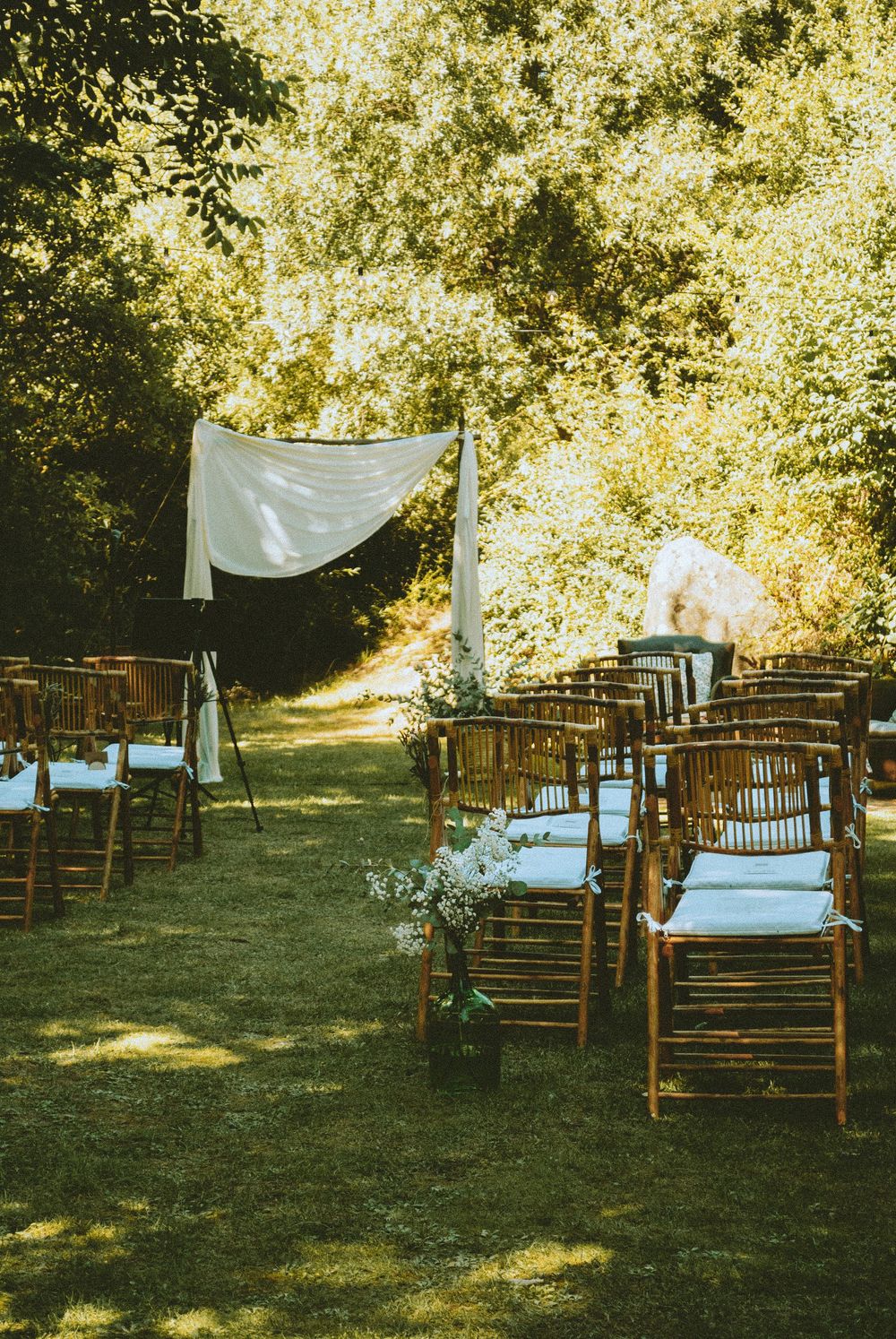 Garden wedding ceremony setup with wooden chairs and natural greenery. Segovia Spain.