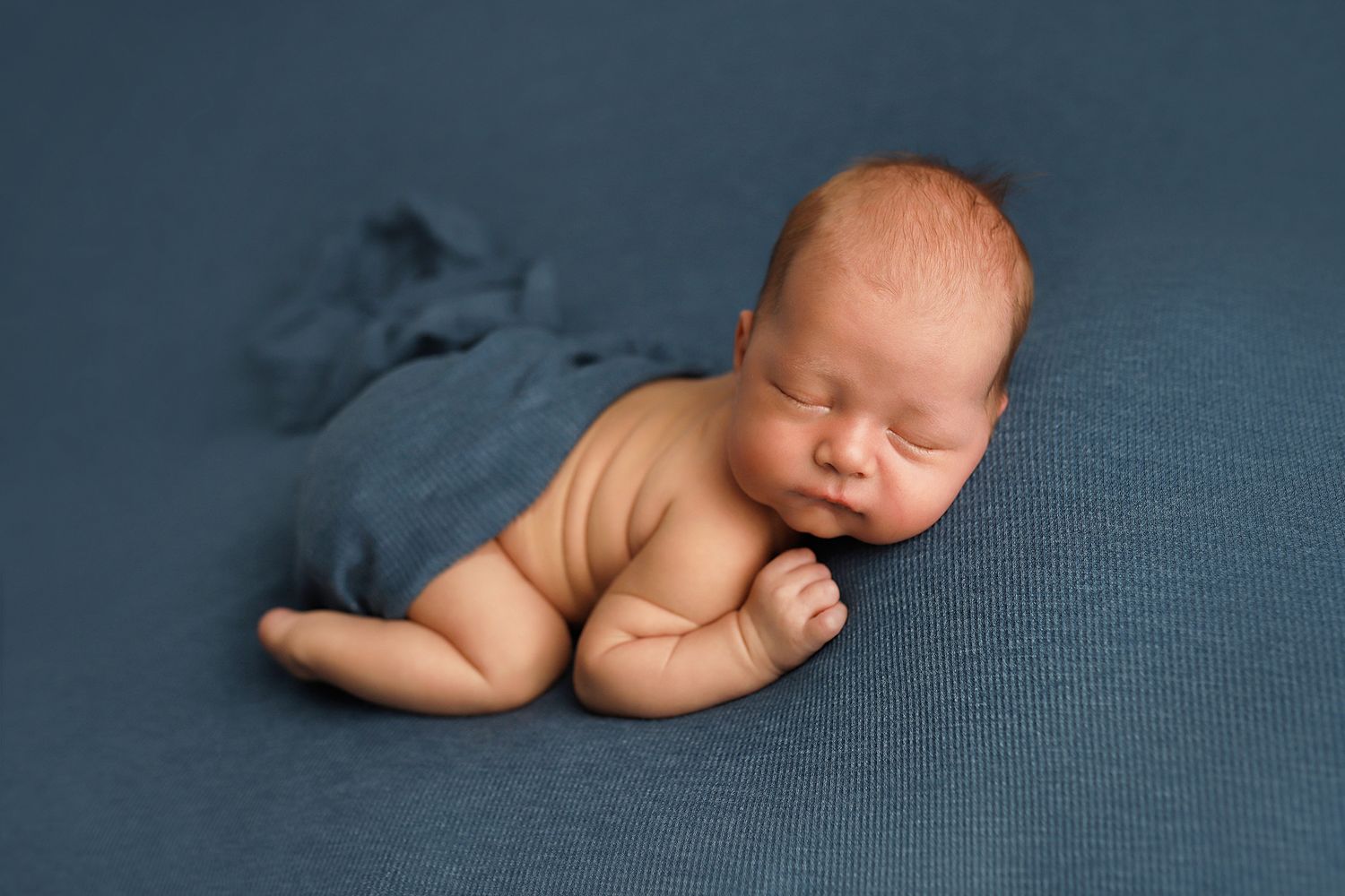 A series of six artistic newborn baby photographs showing peaceful sleeping poses on a blue textured backdrop.