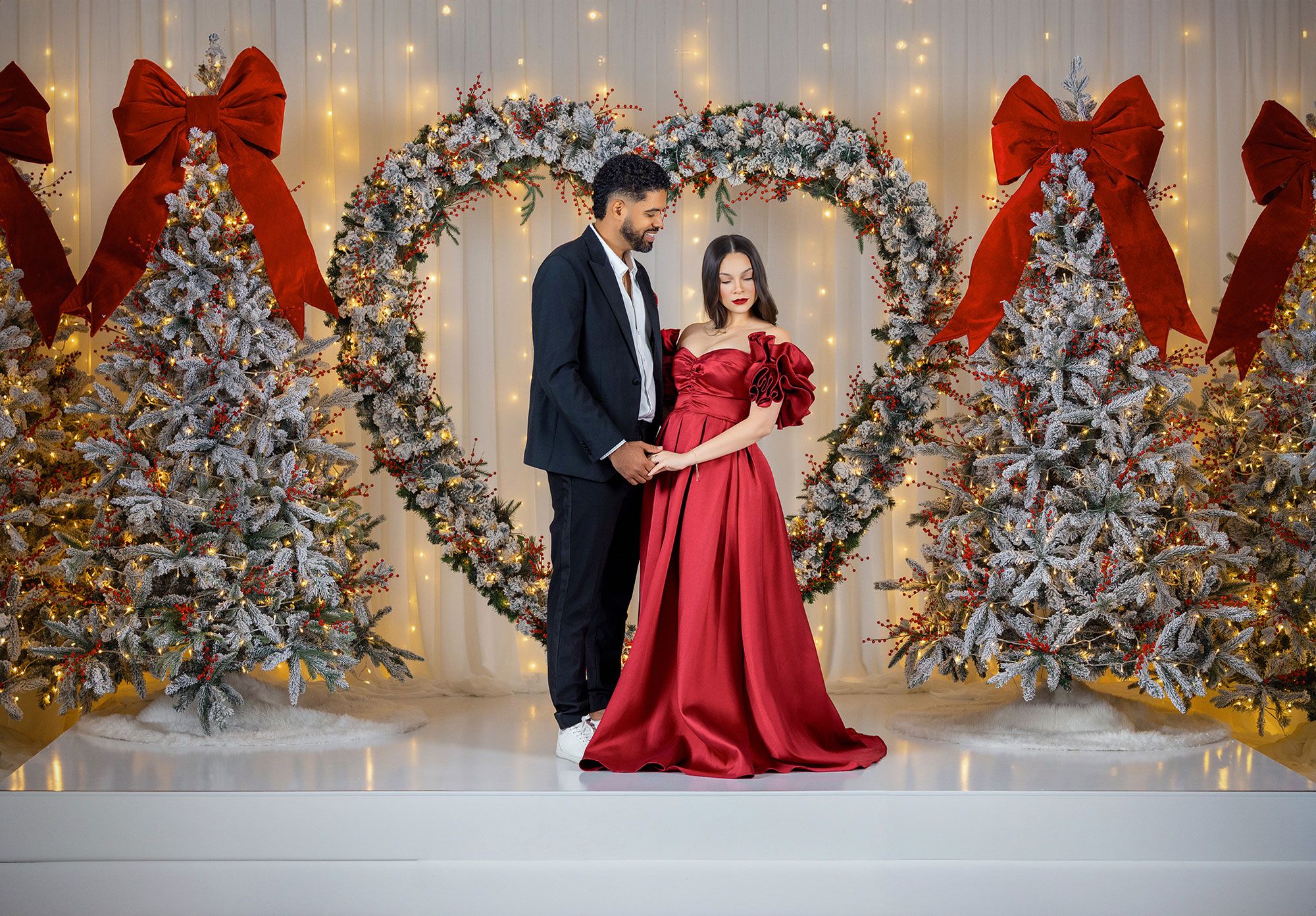 Elegant holiday scene with figures in formal attire posing by decorated Christmas trees and twinkling lights.