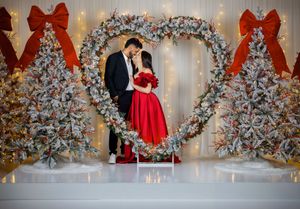 Festive holiday portrait session featuring white Christmas trees, red bows, and soft lighting effects.