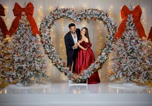 Romantic holiday photoshoot featuring decorated Christmas trees, string lights, and red accents.