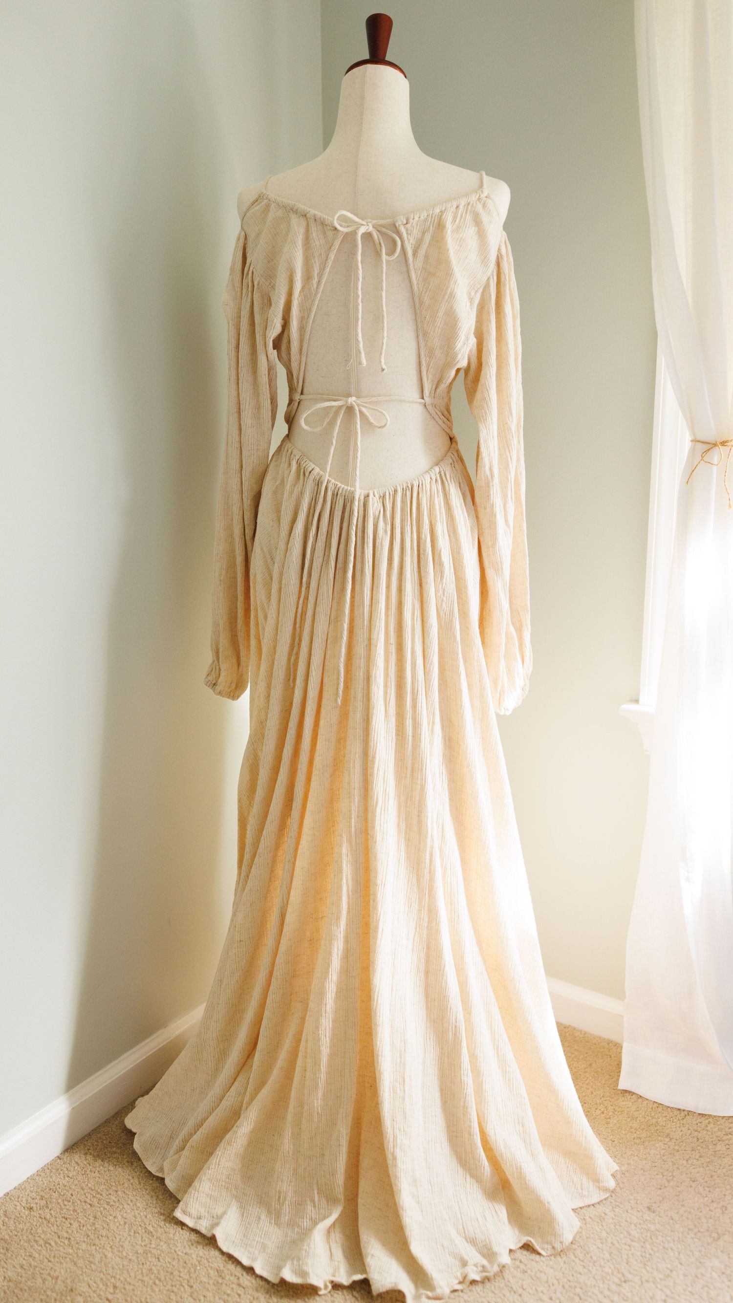 Vintage cream-colored peasant dress with puff sleeves and corset back lacing displayed on mannequin from multiple angles.