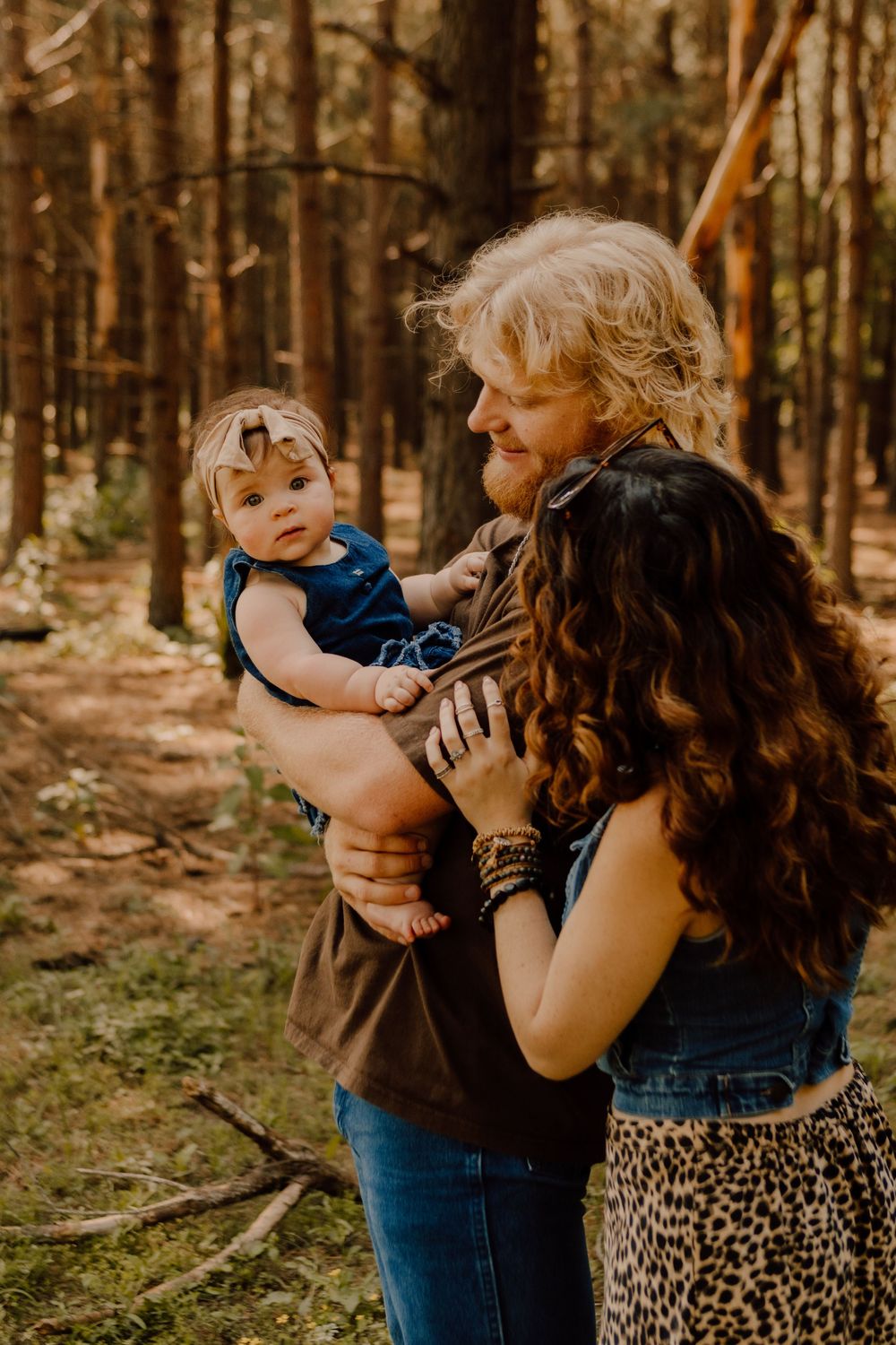 A family shares tender moments together in a sunlit forest setting with warm autumn tones.