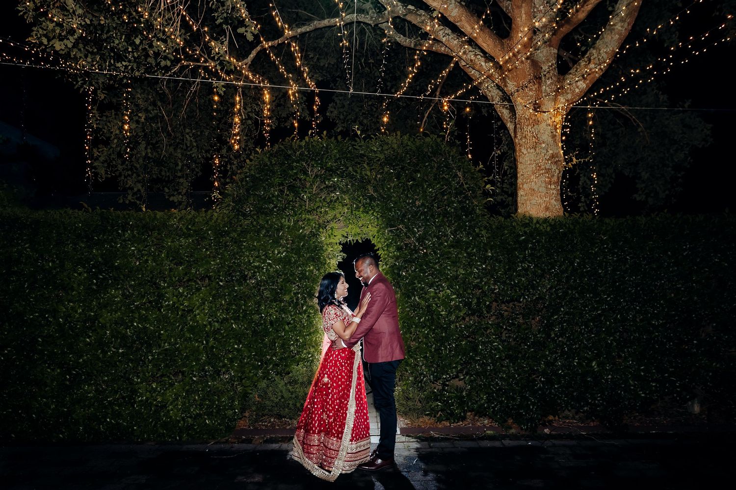 A beautiful outdoor wedding ceremony under a white gazebo surrounded by guests in a garden setting.