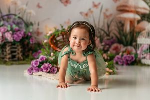 Child photo session with enchanted garden backdrop featuring butterflies and flowers.