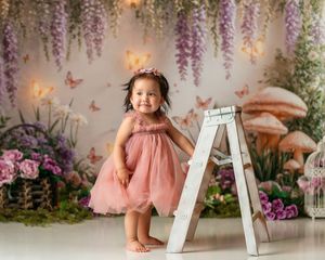 Floral backdrop with hanging wisteria and pink roses creates a dreamy garden setting for a photo session.