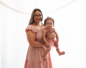 Family portrait session with coordinating pink outfits against white studio backdrop.