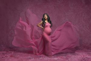 Artistic newborn portrait with flowing burgundy fabric in dramatic lighting.