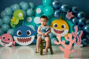 Baby shark themed party setup with blue and turquoise balloons and cute sea creature decorations.