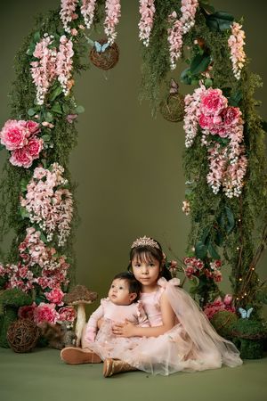 Enchanted garden setting with hanging pink wisteria and roses creates a magical backdrop.