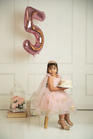 Pink tulle dress and rose gold number 5 balloon create an elegant birthday photo setting.