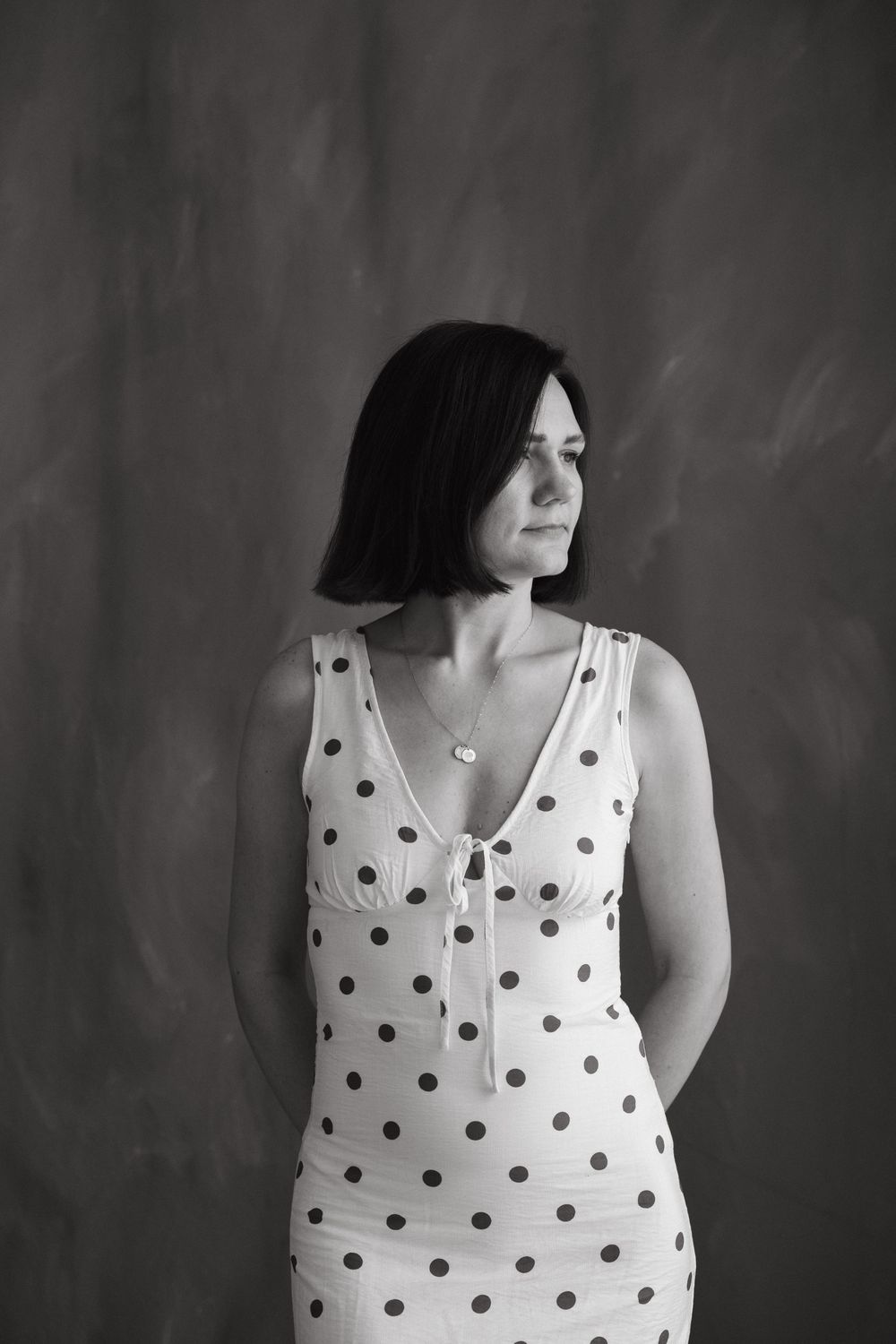 A minimalist black and white photo series showing a figure in a black dress against a white wall creating abstract poses.