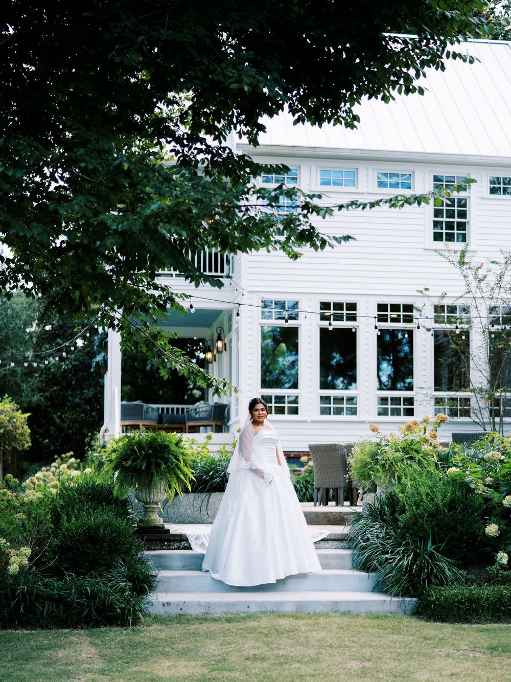 Bridal portraits in a garden setting with white columns and greenery against a classic white building backdrop.
