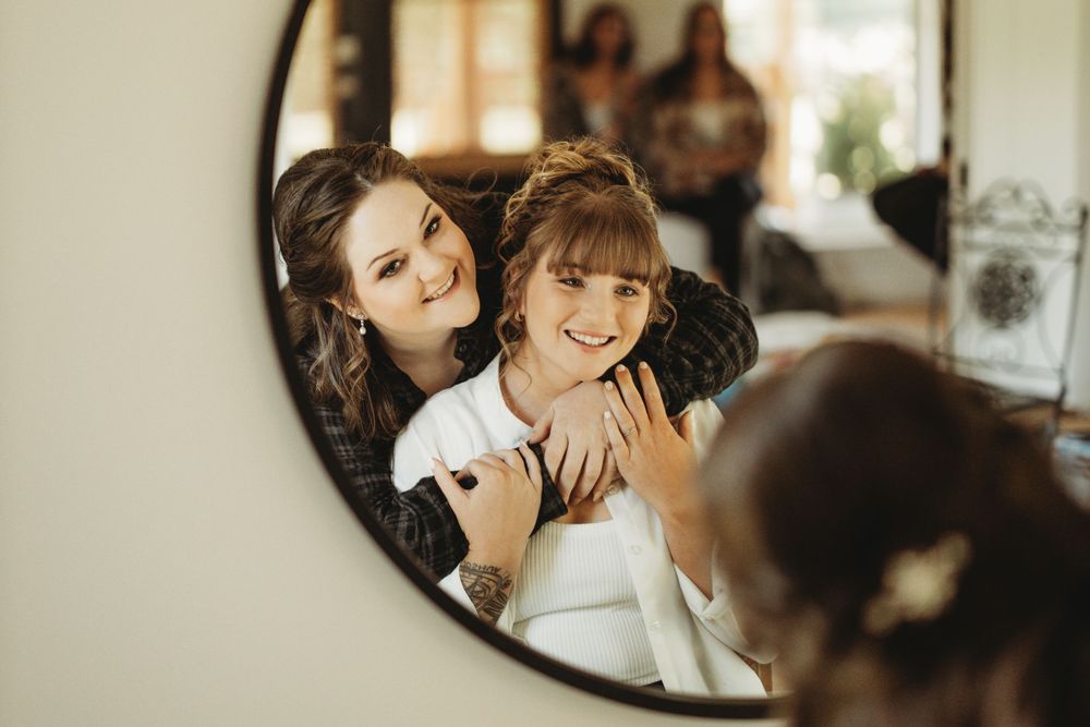 Getting ready moments captured in mirror reflections with soft natural lighting.