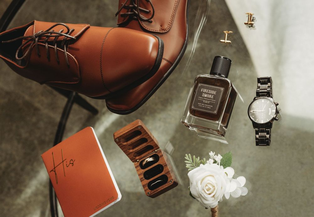 Wedding accessories including brown leather shoes and perfume bottles arranged artistically.
