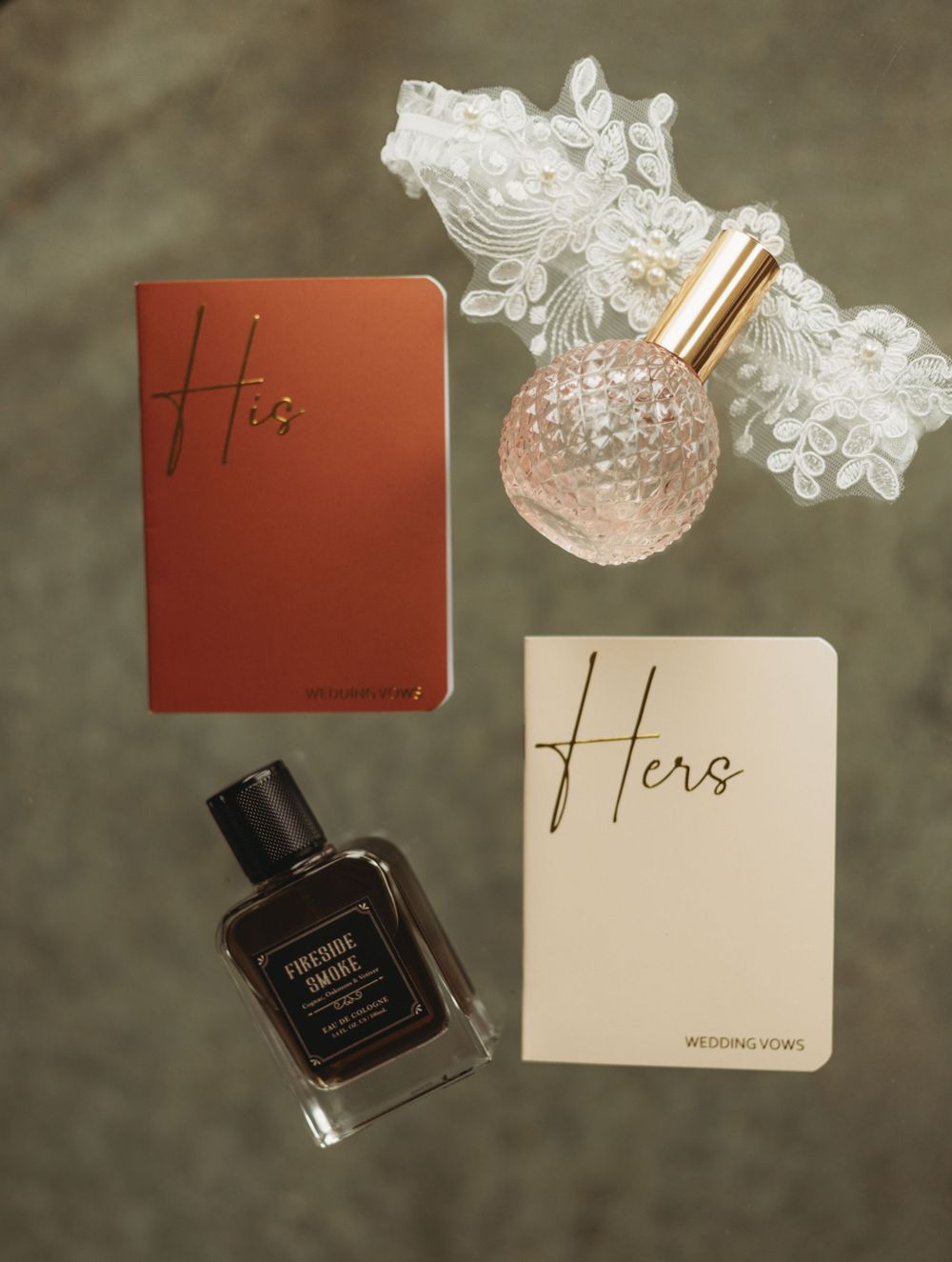 Wedding detail shots of vow books and perfume bottles on dark background.