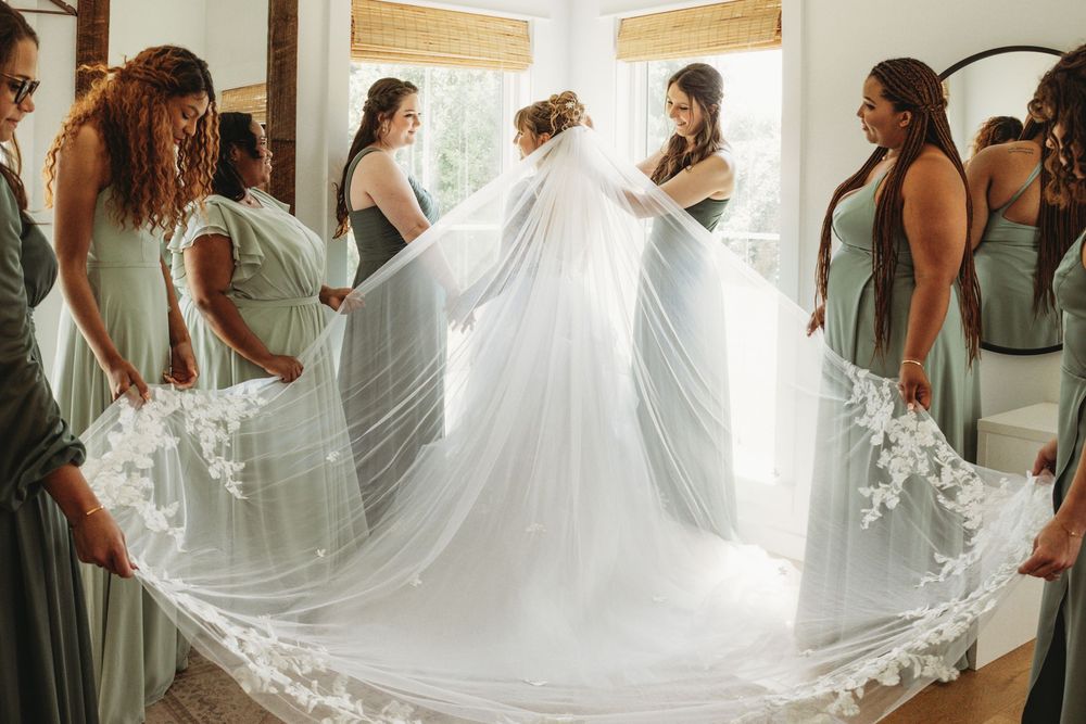 Bridesmaids helping with wedding dress in bright indoor setting.