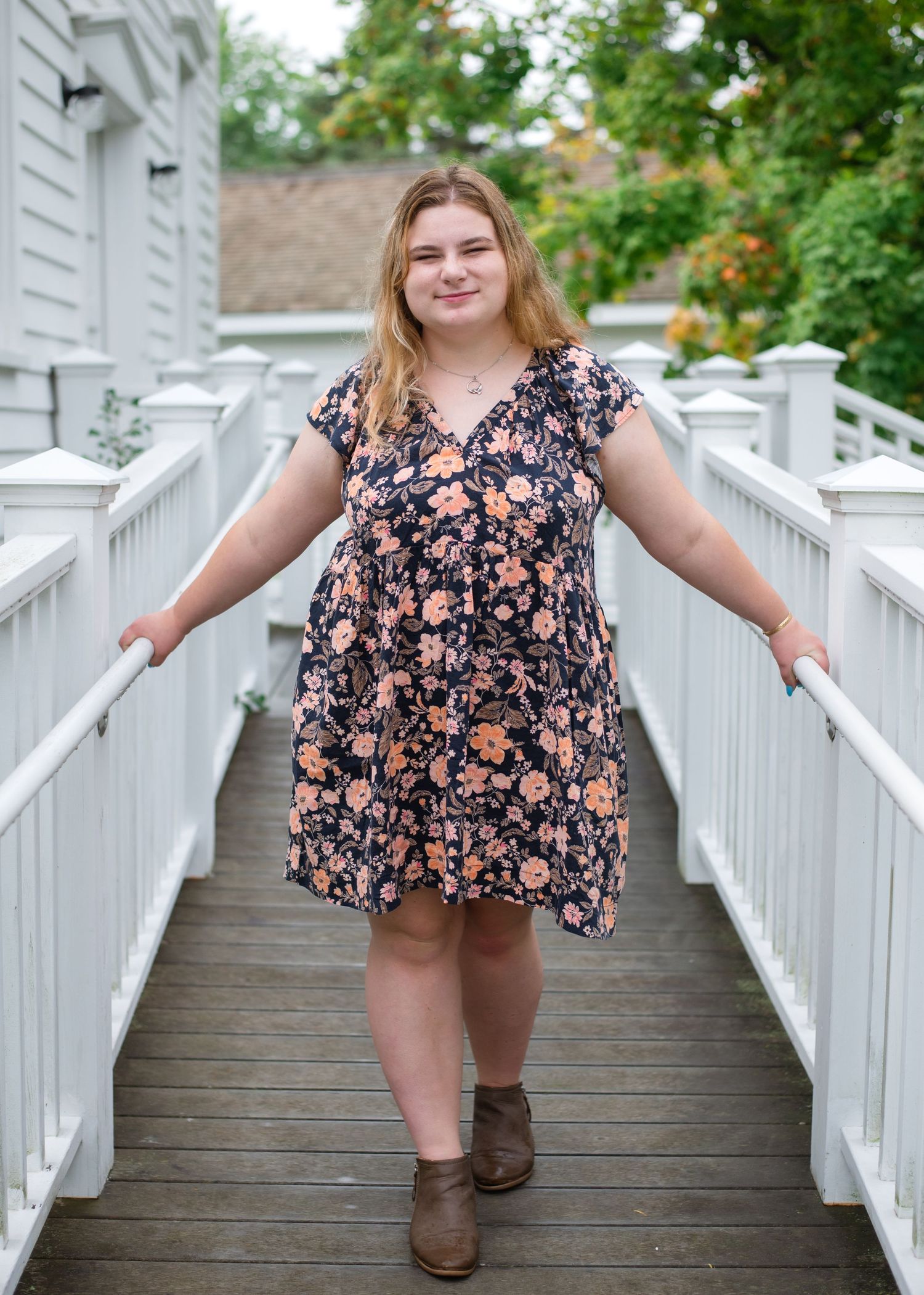 A person in a floral top and brown boots poses on a white wooden deck in three similar candid shots.