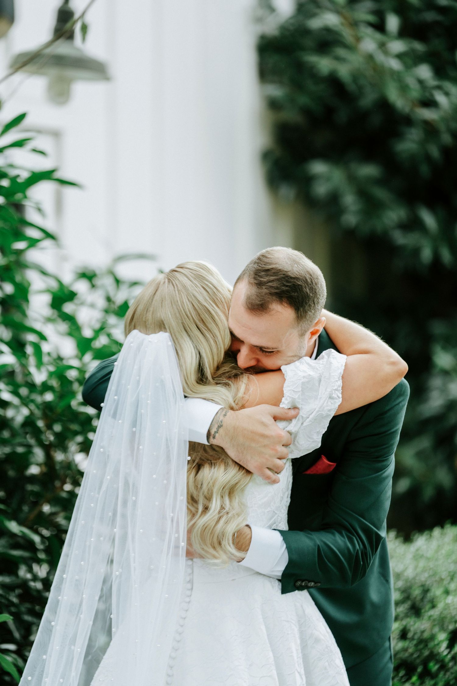 A romantic wedding moment captured in a garden setting with flowing white veil and elegant attire.