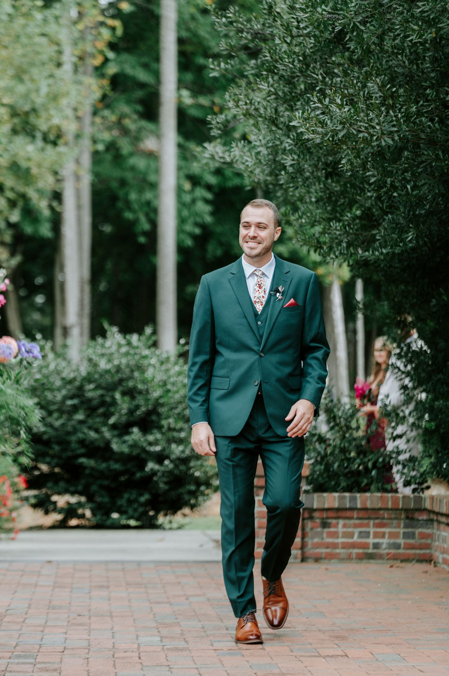 Four sequential photos showing someone in a dark green suit and brown shoes walking on a brick pathway.