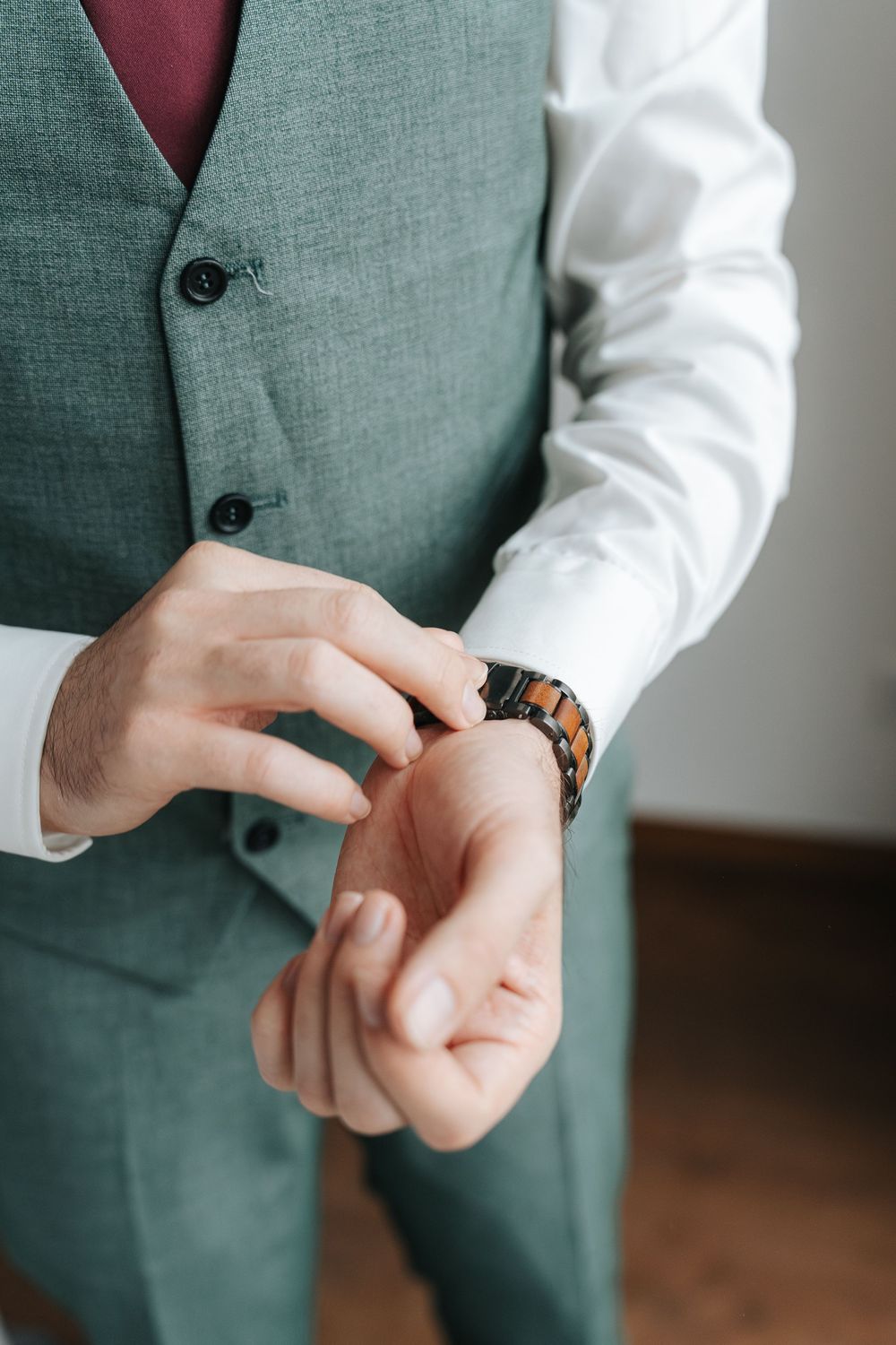 Close-up sequence showing someone in a gray vest adjusting their wooden wristwatch.