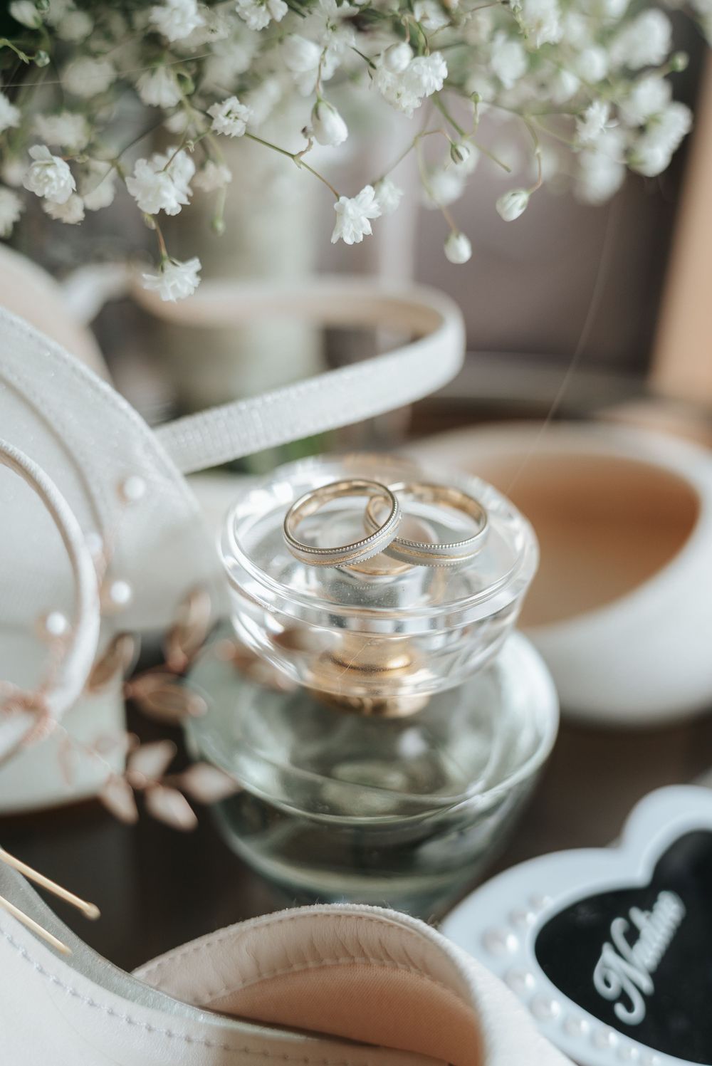 White cherry blossoms delicately arranged above glass bowls and white linens in a soft, minimalist table setting.