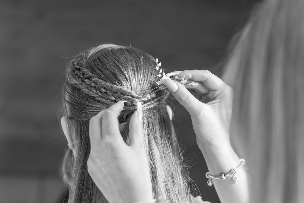 A bride has her hair styled and arranged in an elegant updo for her wedding day.