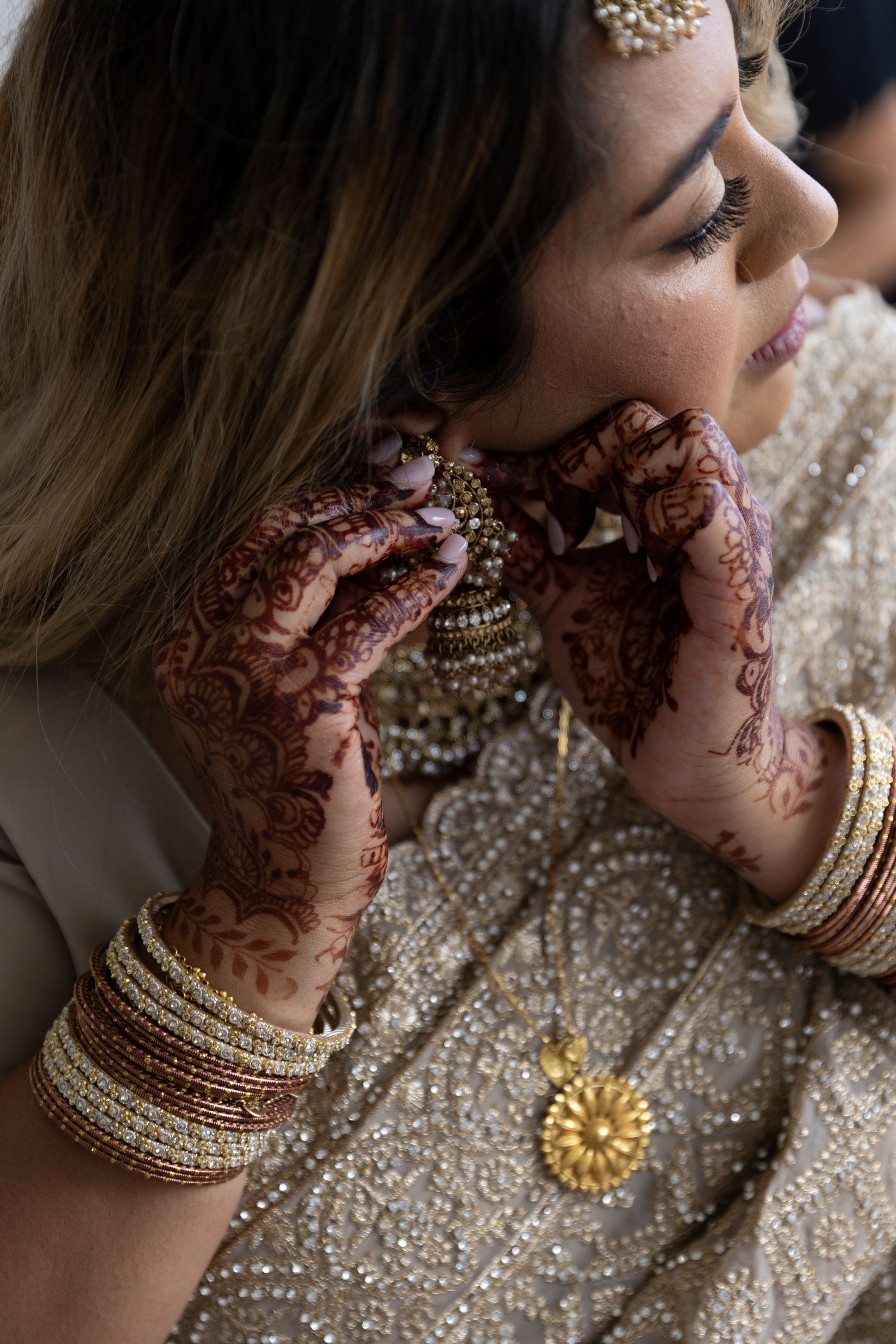 Detailed view of intricate henna designs and traditional Indian bridal jewelry on hands and neck.