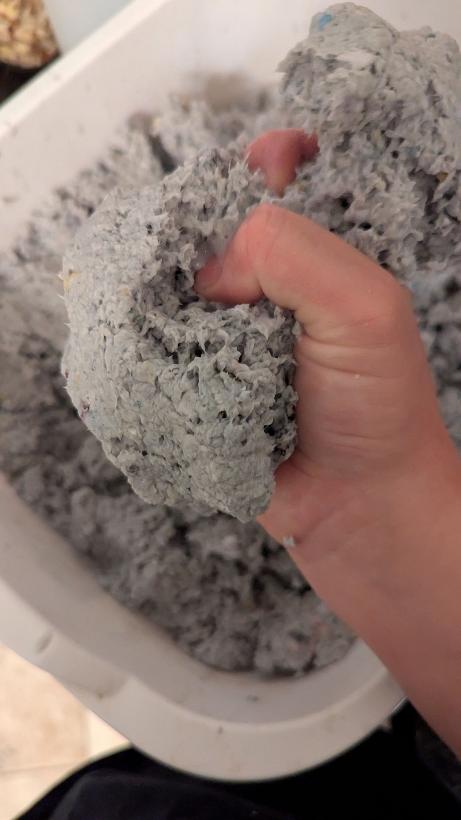 A hand squishes some paper mache clay.