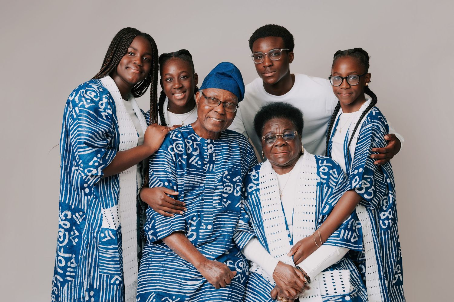 A family wearing coordinating blue and white patterned outfits poses together for a portrait session.