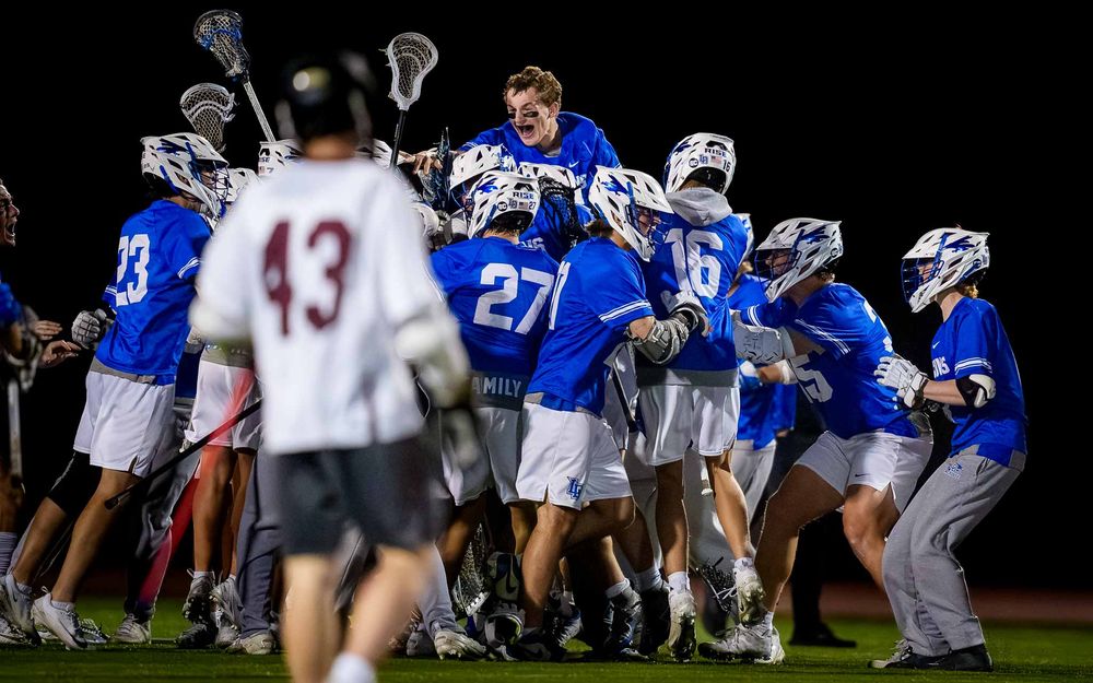 Lower Dauphin lacrosse team rushing the field in celebration after the 2026 Mid Penn Championship win by SportsFox Photography, Hershey PA.