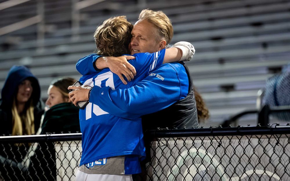 Lower Dauphin lacrosse player hugging his father in the stands after the 2026 Mid Penn Championship by SportsFox Photography, Hershey PA.