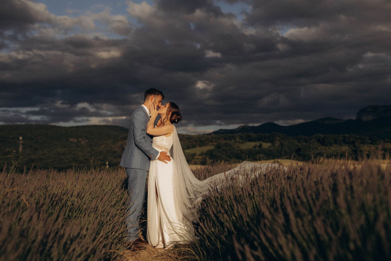 A romantic black and white wedding photograph showing a tender embrace in a natural outdoor setting.