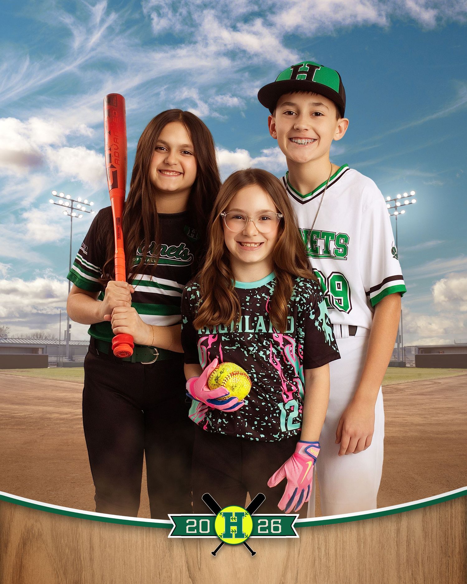 Three youth baseball players in green and black uniforms pose together on a field, holding a bat and softball.