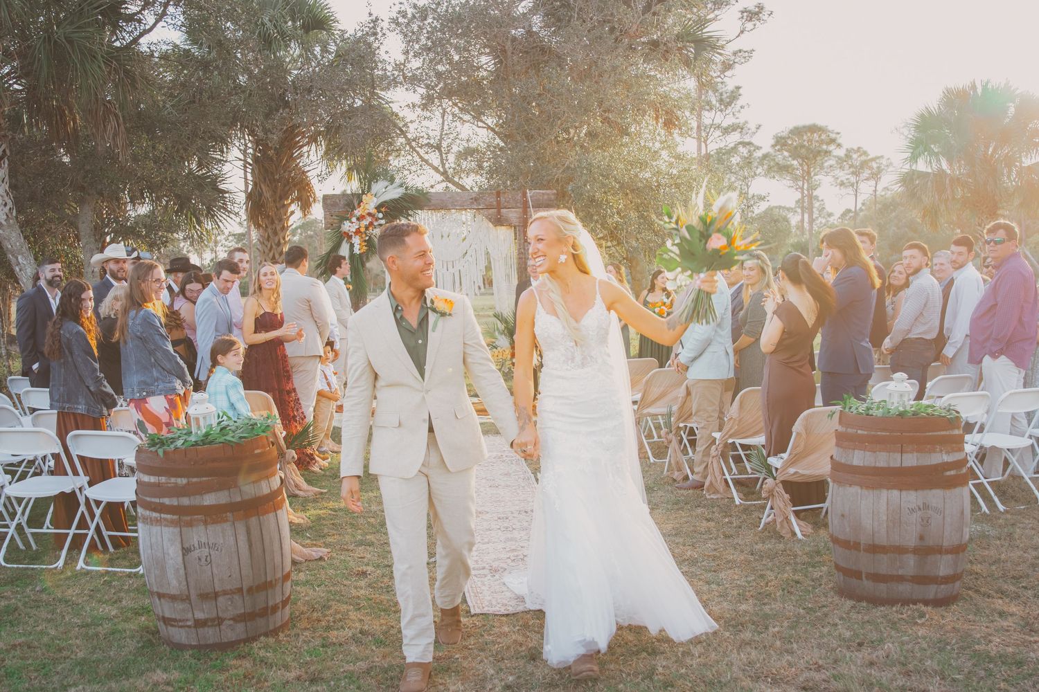 A newly married couple walks down the aisle during an outdoor wedding ceremony at The Barn at Palmetto Flats in Fort Pierce, FL