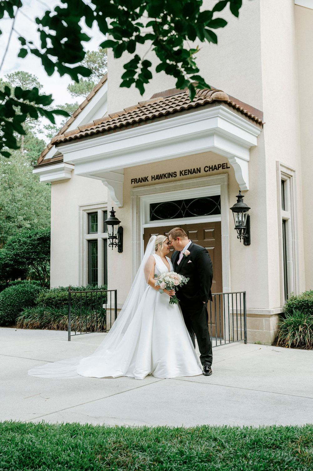 Bride and groom share romantic moment outside Frank Hawkins Kenan Chapel on their wedding day.