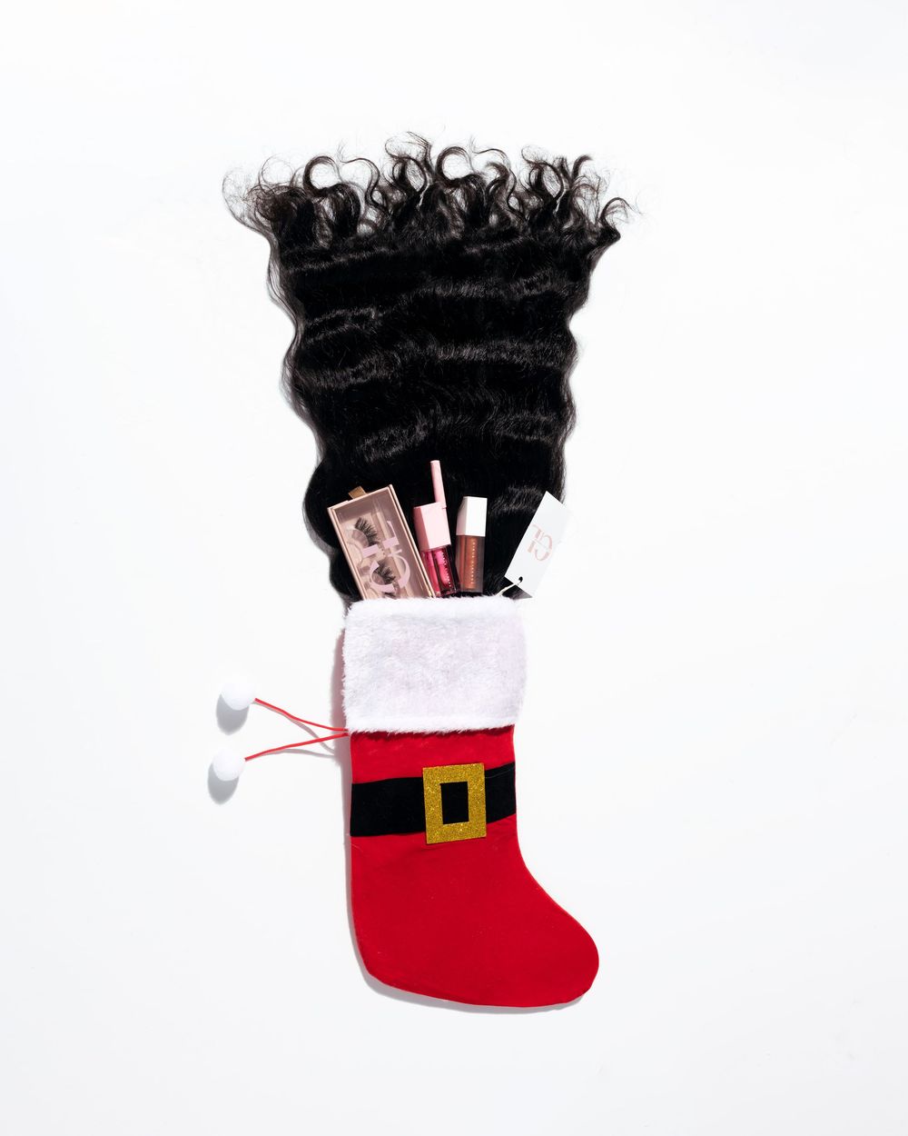 A Christmas stocking filled with beauty products, money, earbuds, and flowing black hair extensions on white background.
