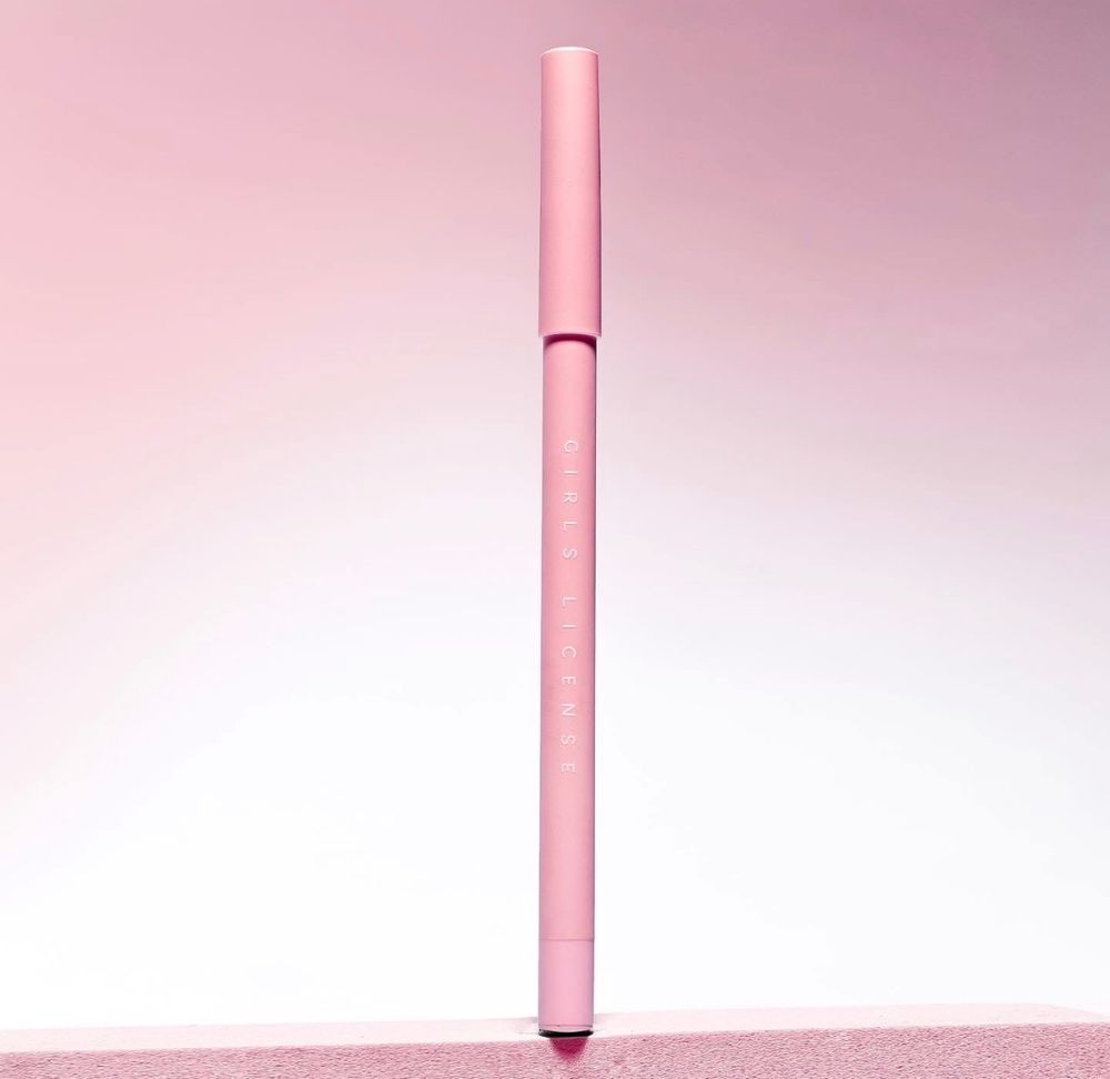Pink makeup lip liner pencil standing upright against a soft pink gradient background.
