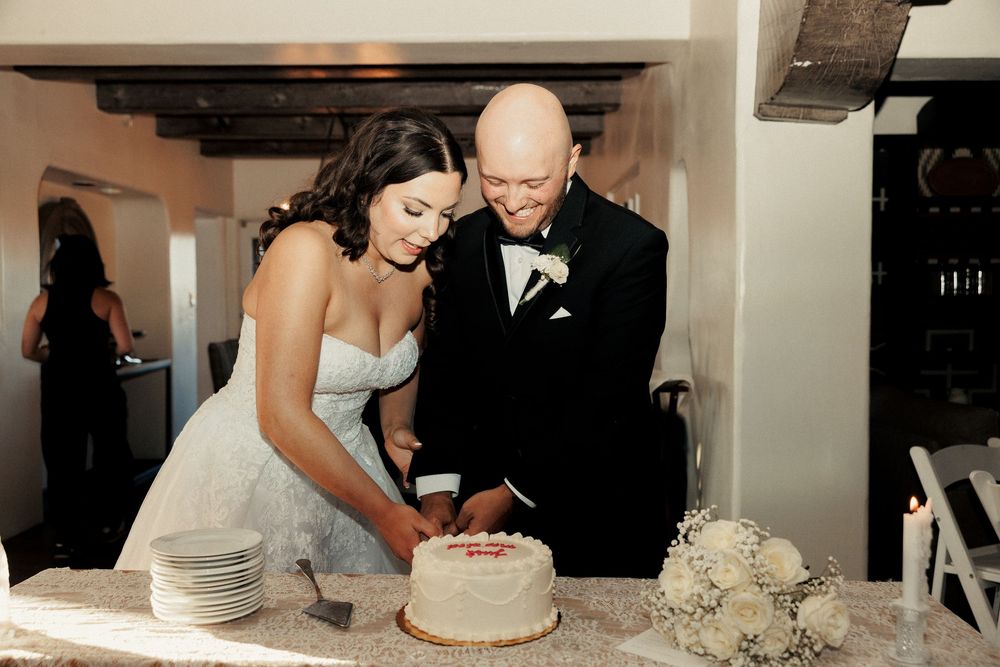 Bride and groom cutting their wedding cake together at a elegant indoor reception venue.