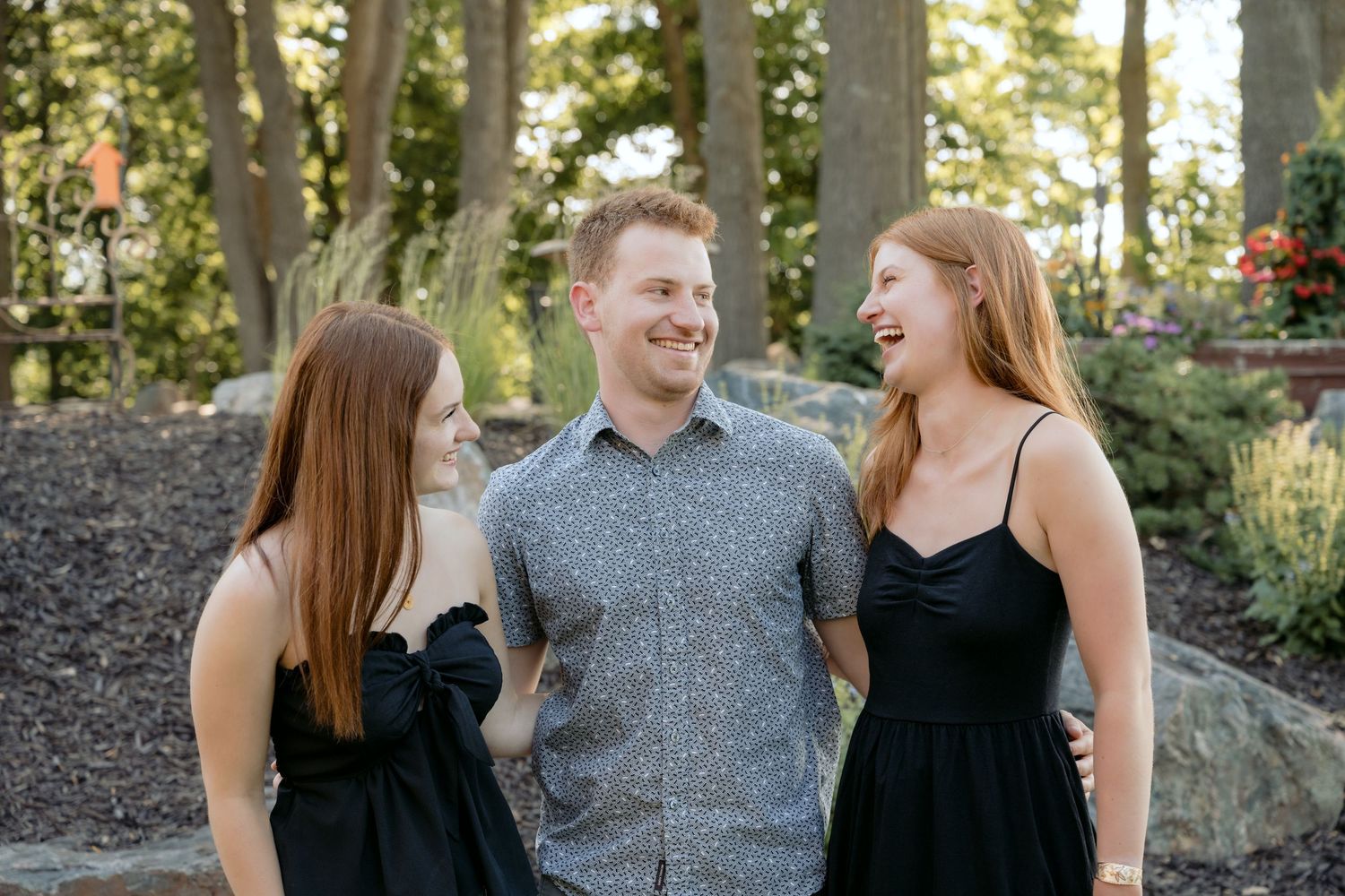 three teenage siblings laughing at each other during summer family portrait session at the cabin on lake wissota in chippewa falls, wi