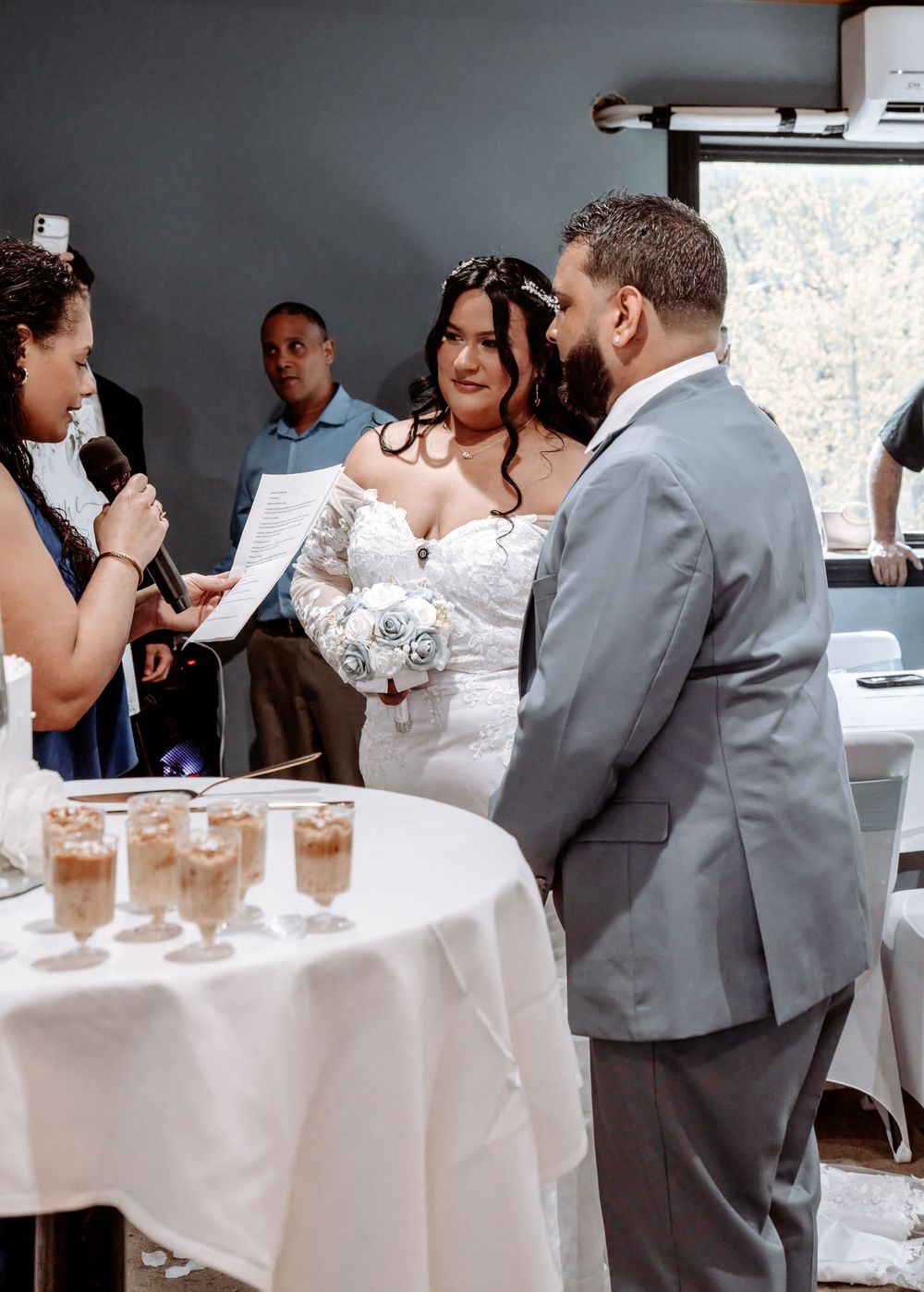 Bride and groom exchange vows during intimate indoor wedding ceremony with officiant and guests.