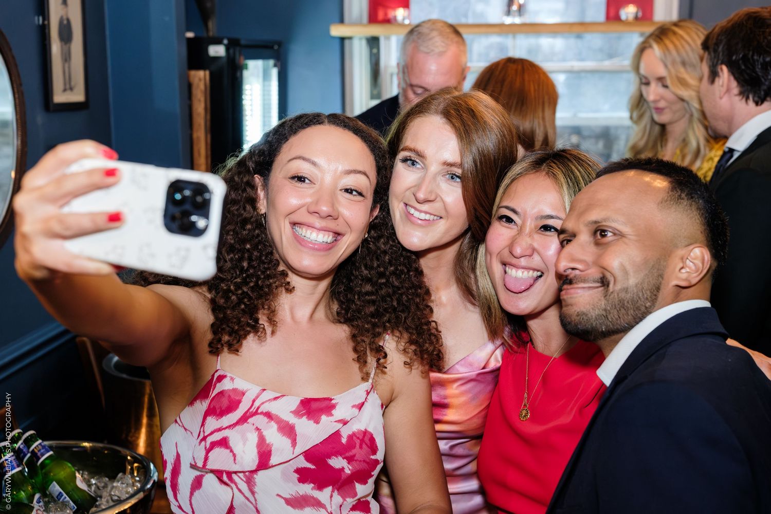 Four friends smiling and taking a selfie together at a social gathering in a stylish indoor venue.