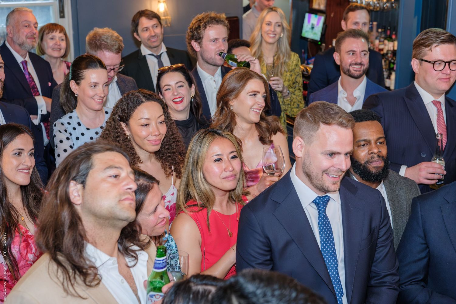 A large group of smiling professionals gathered at an indoor networking event or party.