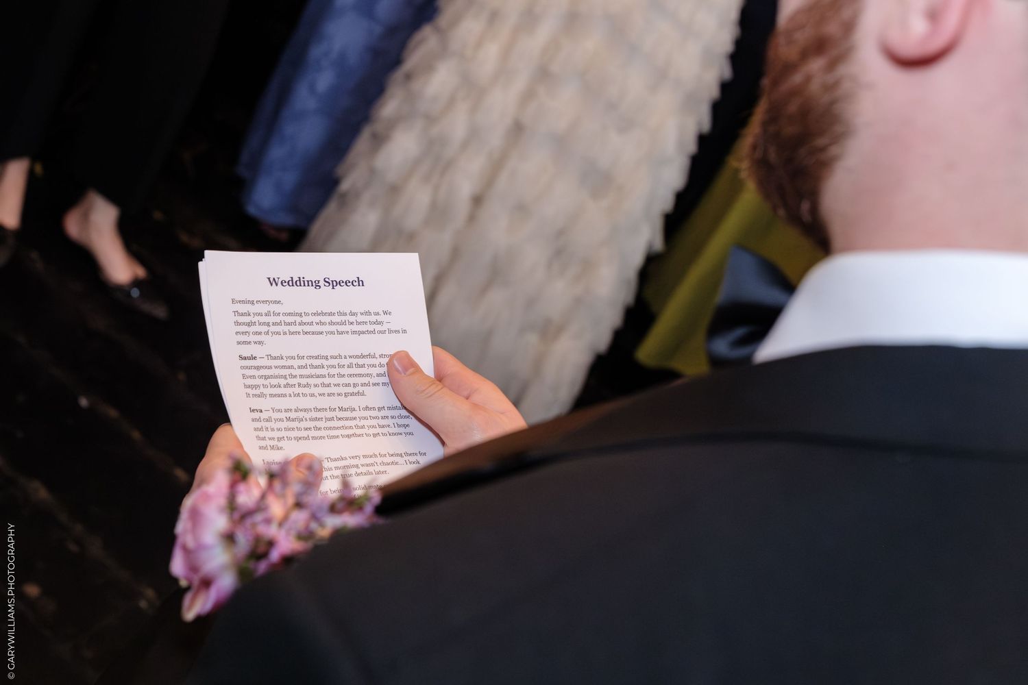 Man in suit reading a printed Wedding Speech paper at a formal ceremony event.