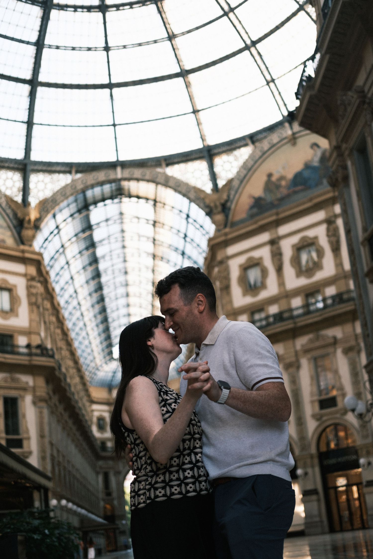 Couple sharing a romantic moment inside the stunning glass-domed Galleria Vittorio Emanuele II in Milan.