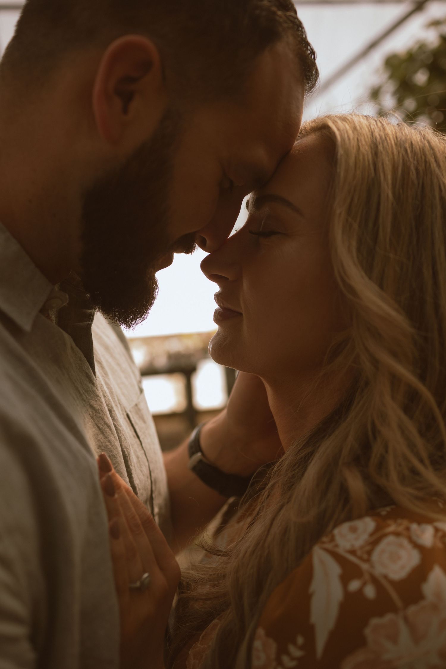 An intimate close-up portrait of a couple sharing a tender moment in warm lighting.