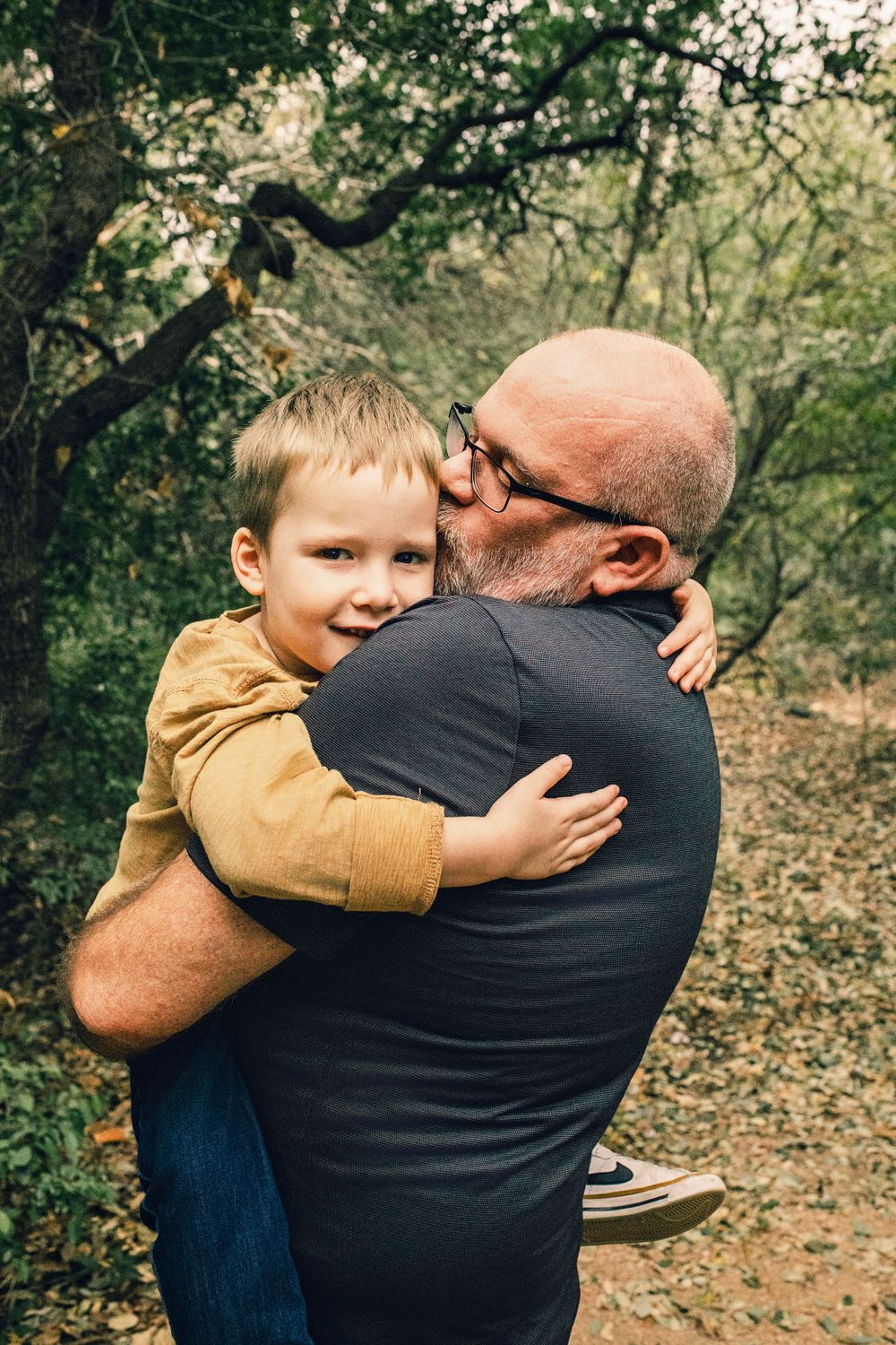 A warm embrace shared between two generations on a wooded nature trail during an autumn day.